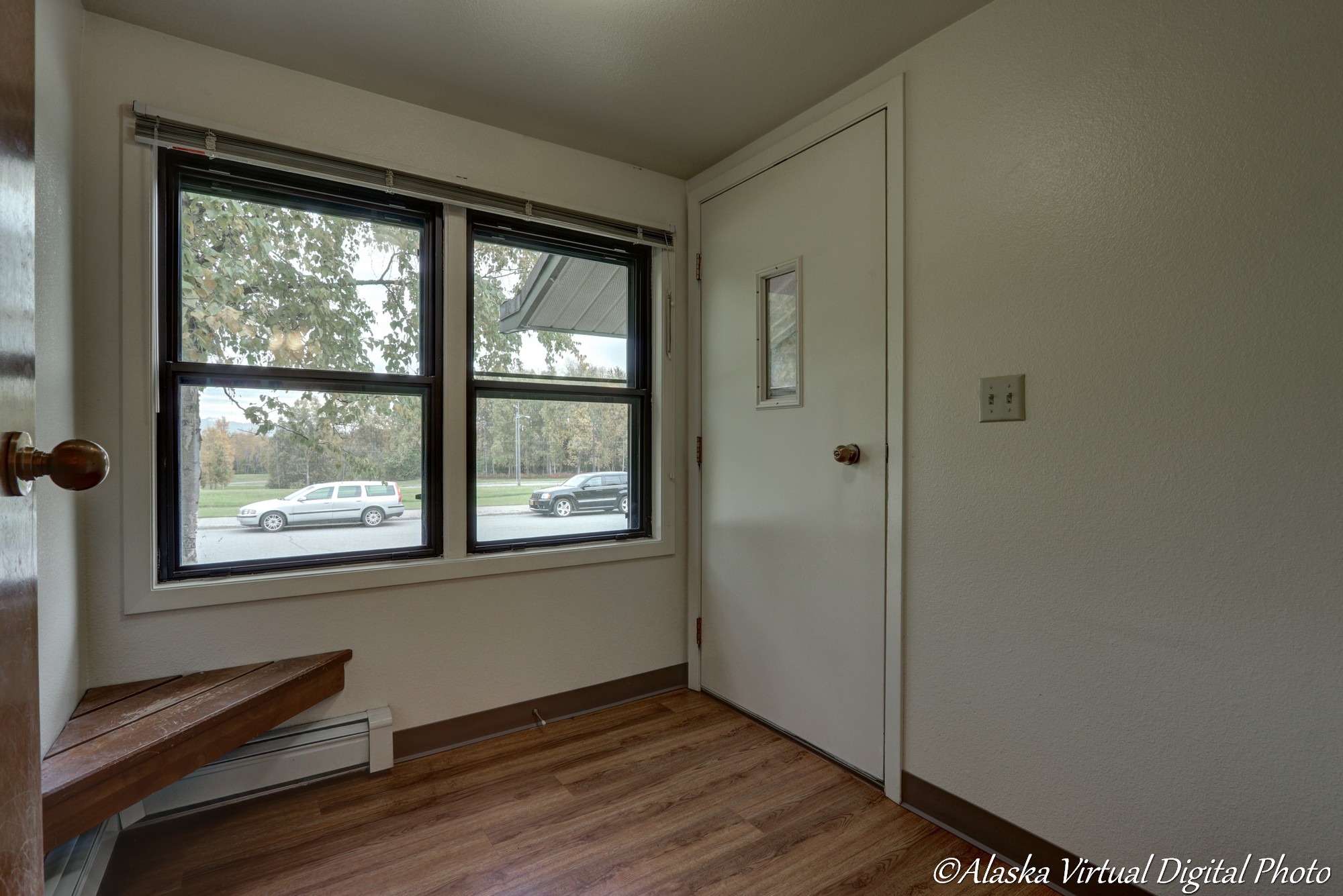 image of arctic entry with wood floors and built in corner wood bench. two windows