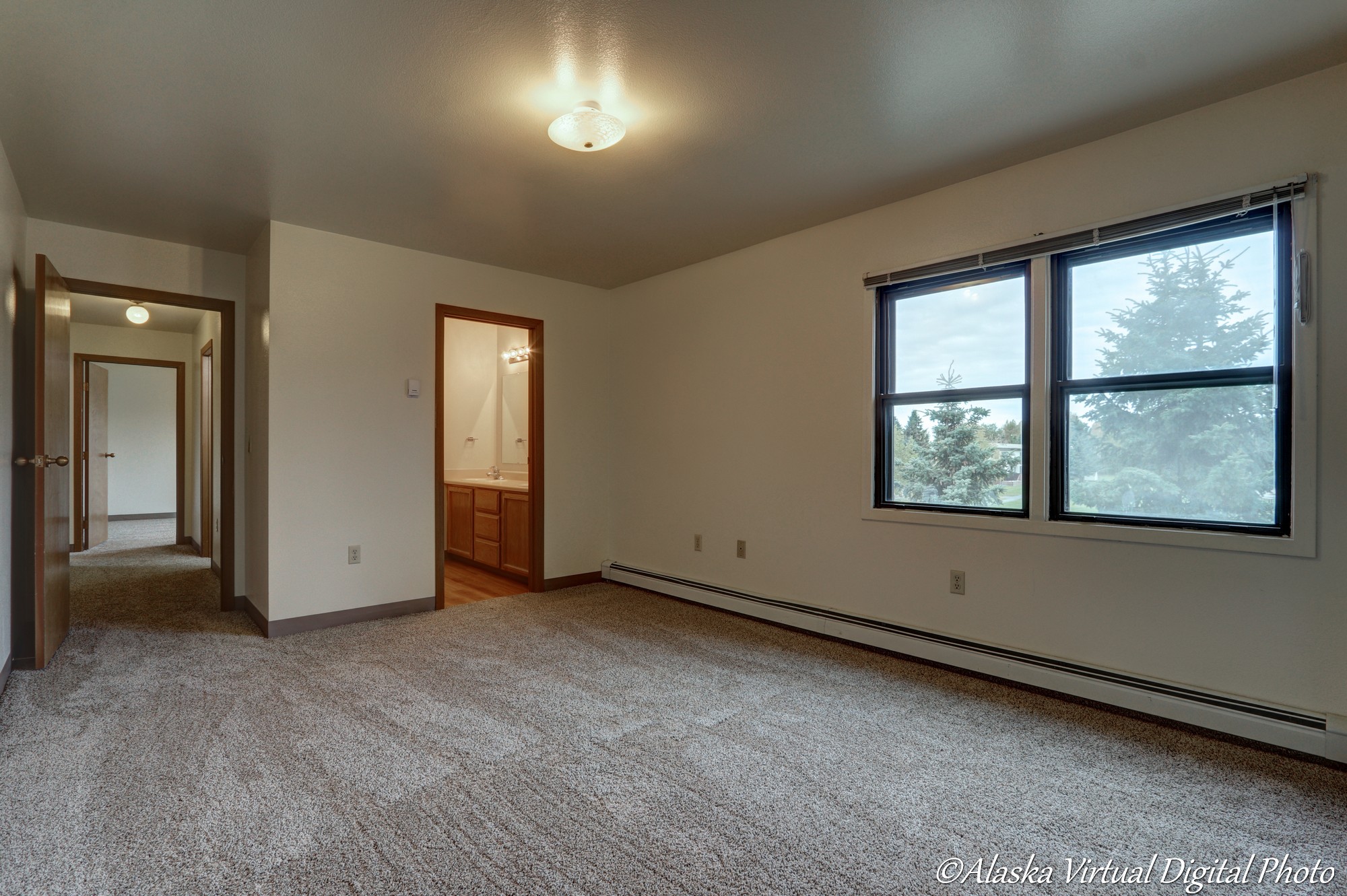 image of mastered bedroom with two windows and view into master bathroom