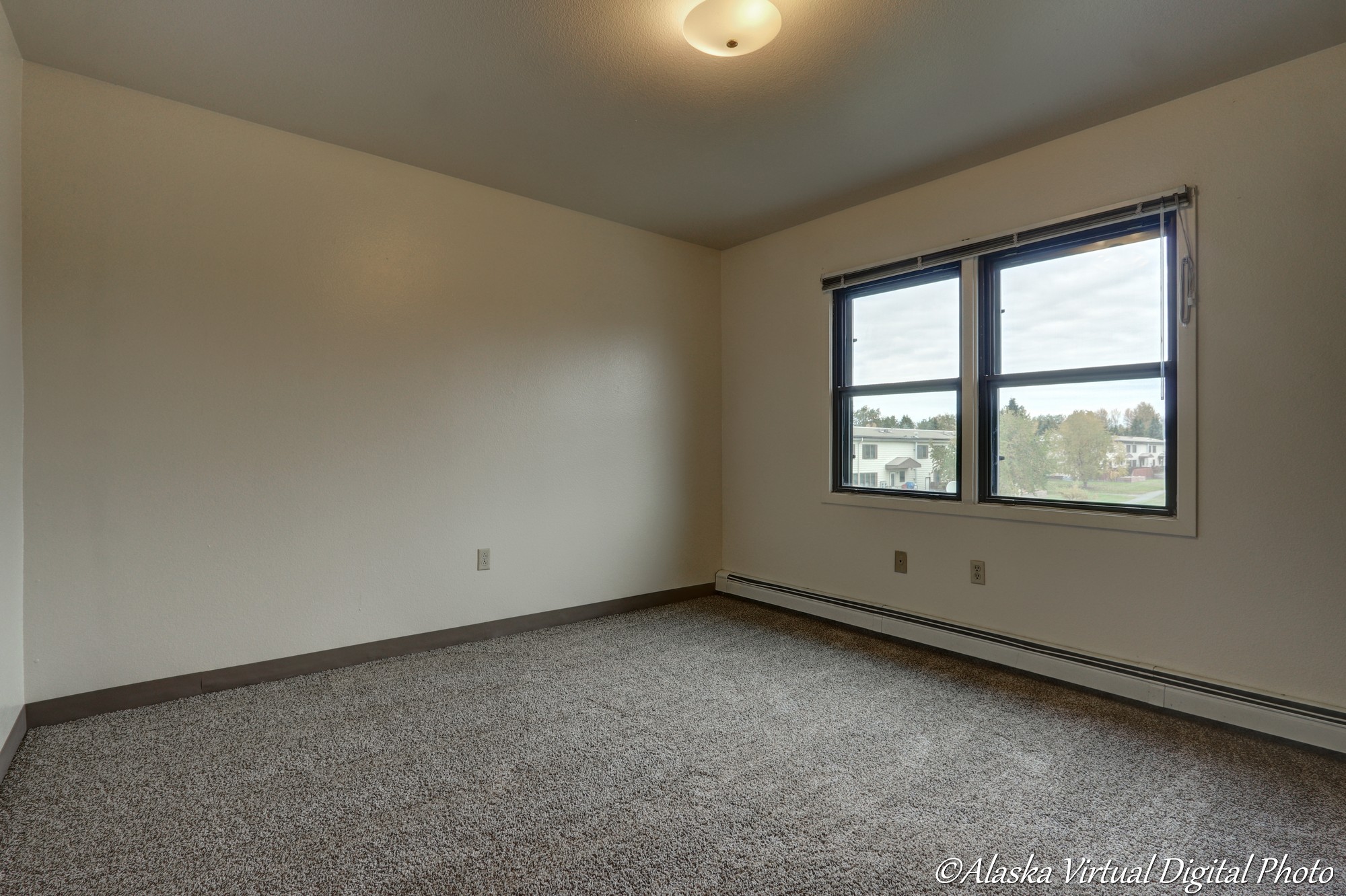 image of carpeted bedroom with two windows overlooking the neighborhood