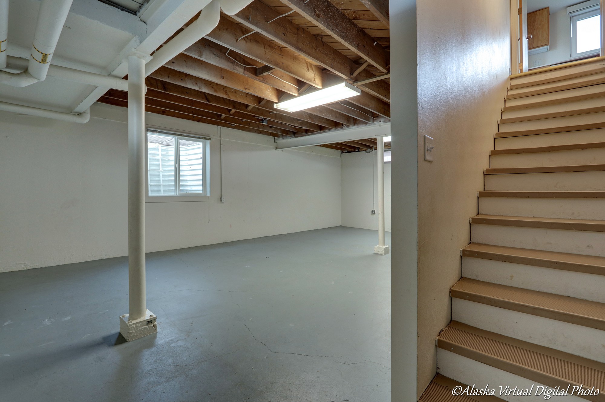 Unfinished basement with blue floor and exposed beams