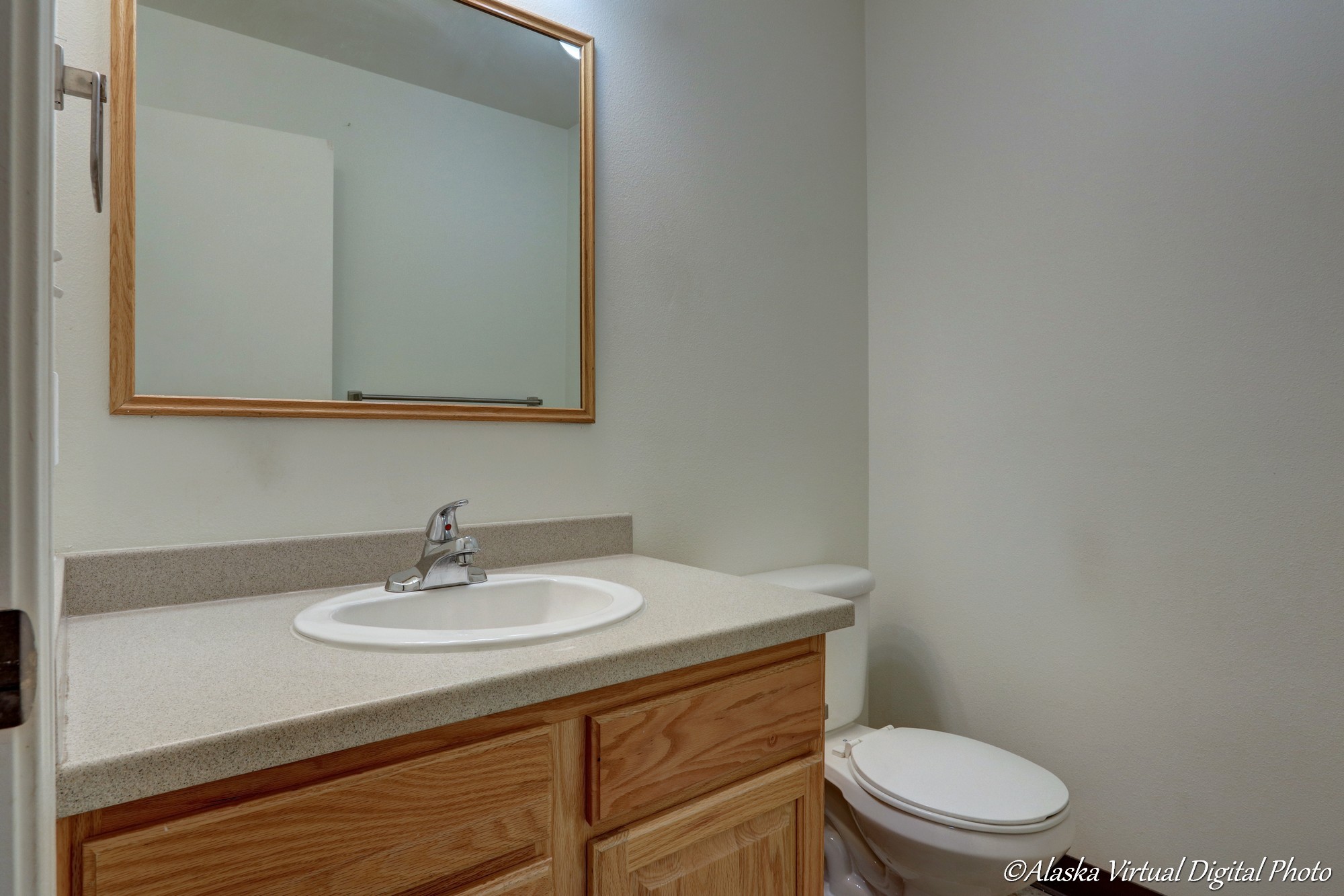 Bathroom with sink, solid surface counters, toilet, and mirror.