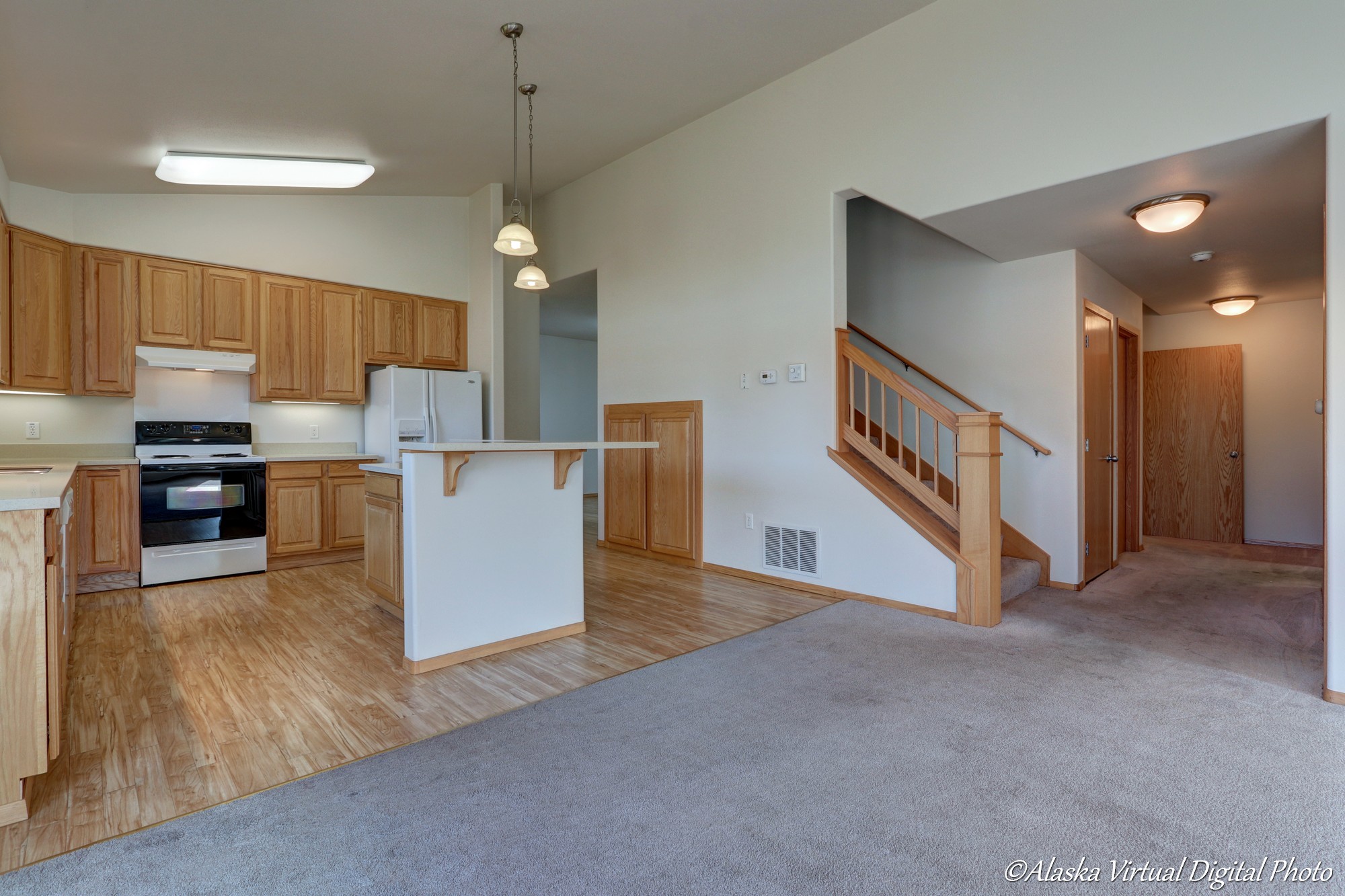 View of kitchen on the left with stairs on the right.