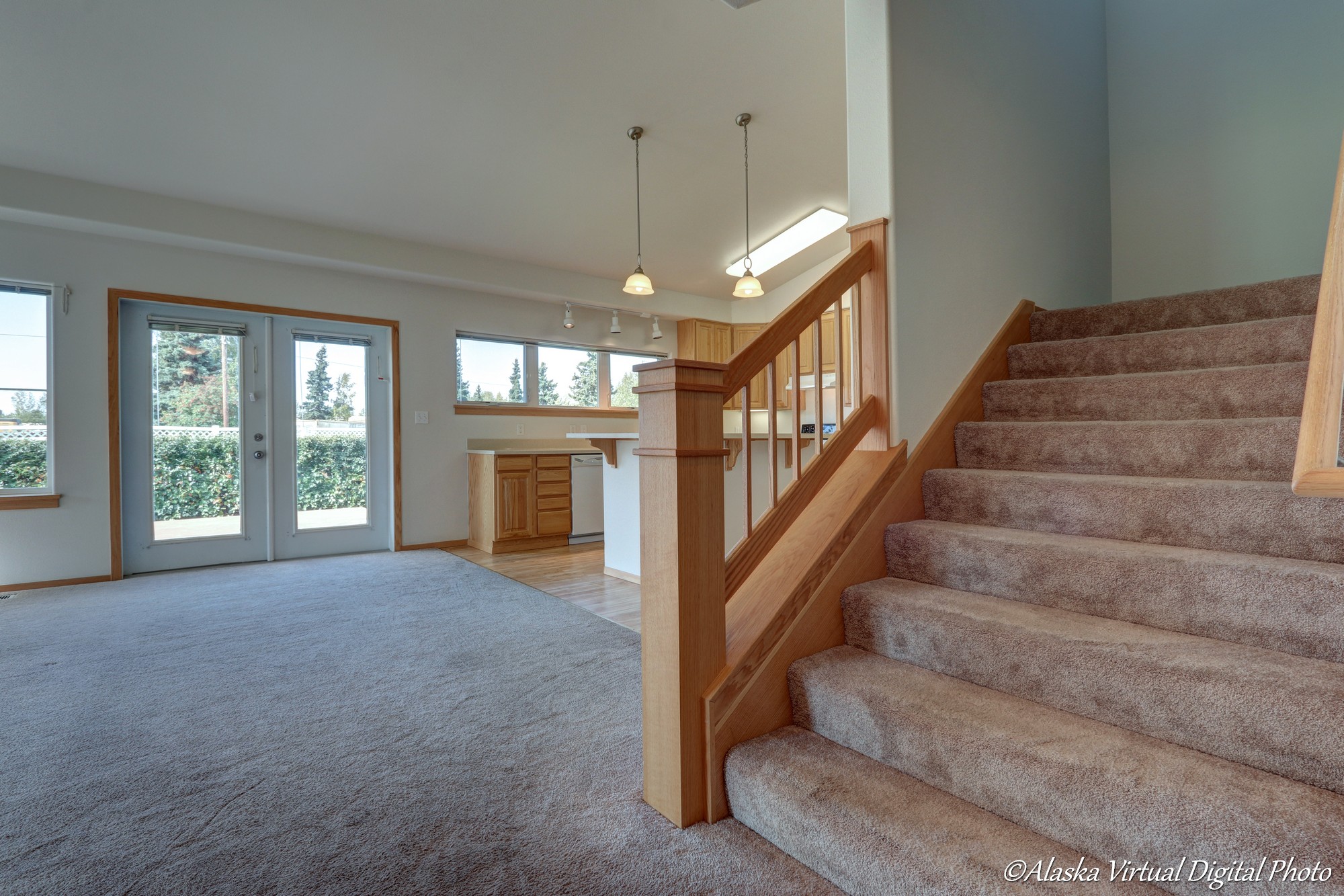 Stairway leading to upstairs on the right with large open living room with vaulted ceilings to the left