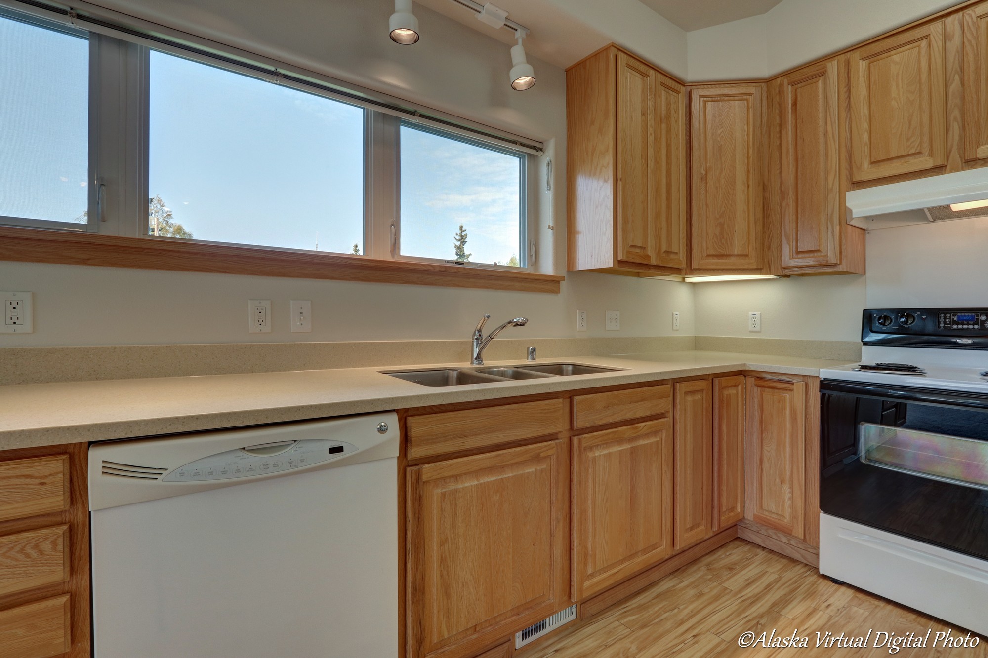 image of kitchen sink under track lights with large windows