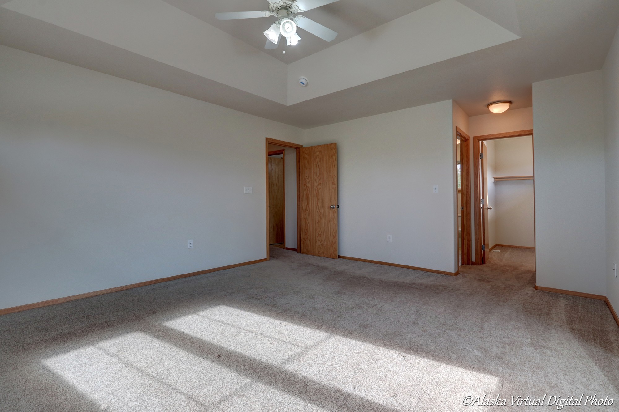 Large master bedroom with fan and raised ceiling