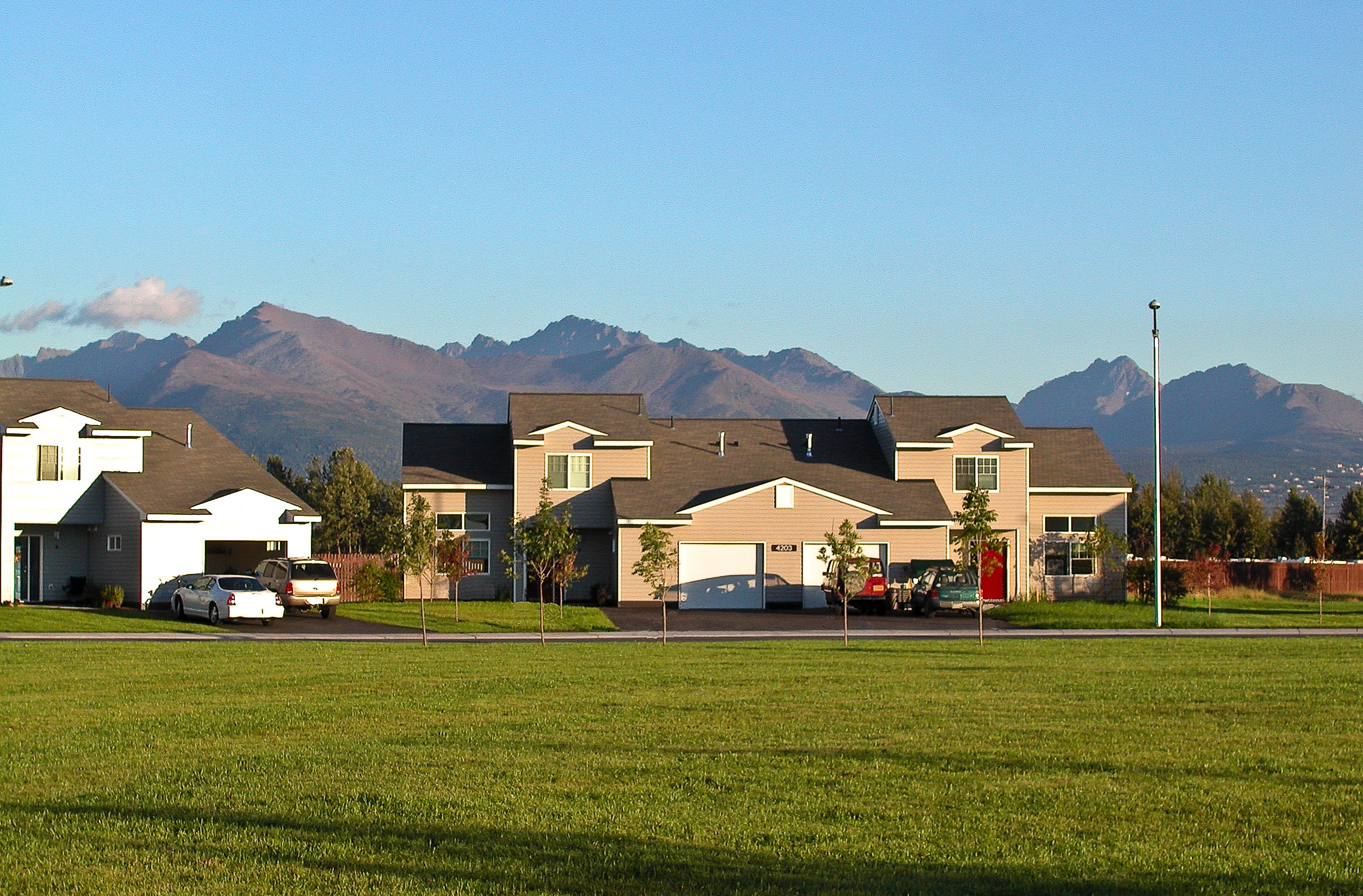 A summer view of a house with mountains behind it.