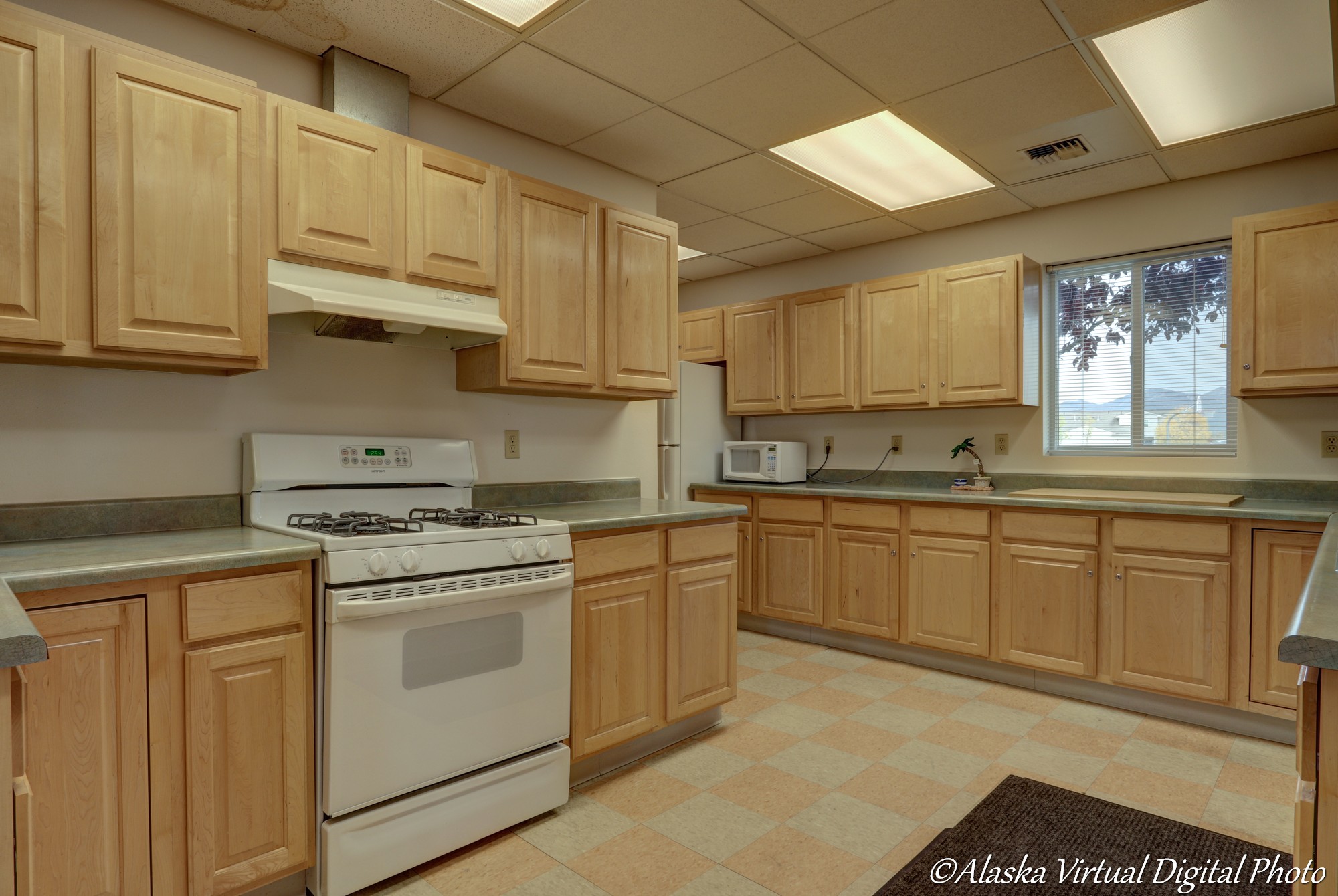 Image of kitchen with checked tile floors and light wooden cabinets