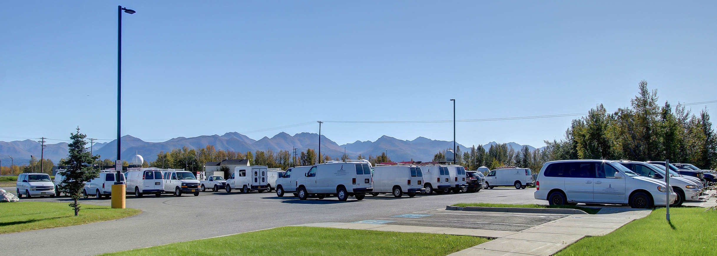 A parking lot full of white maintenance vans