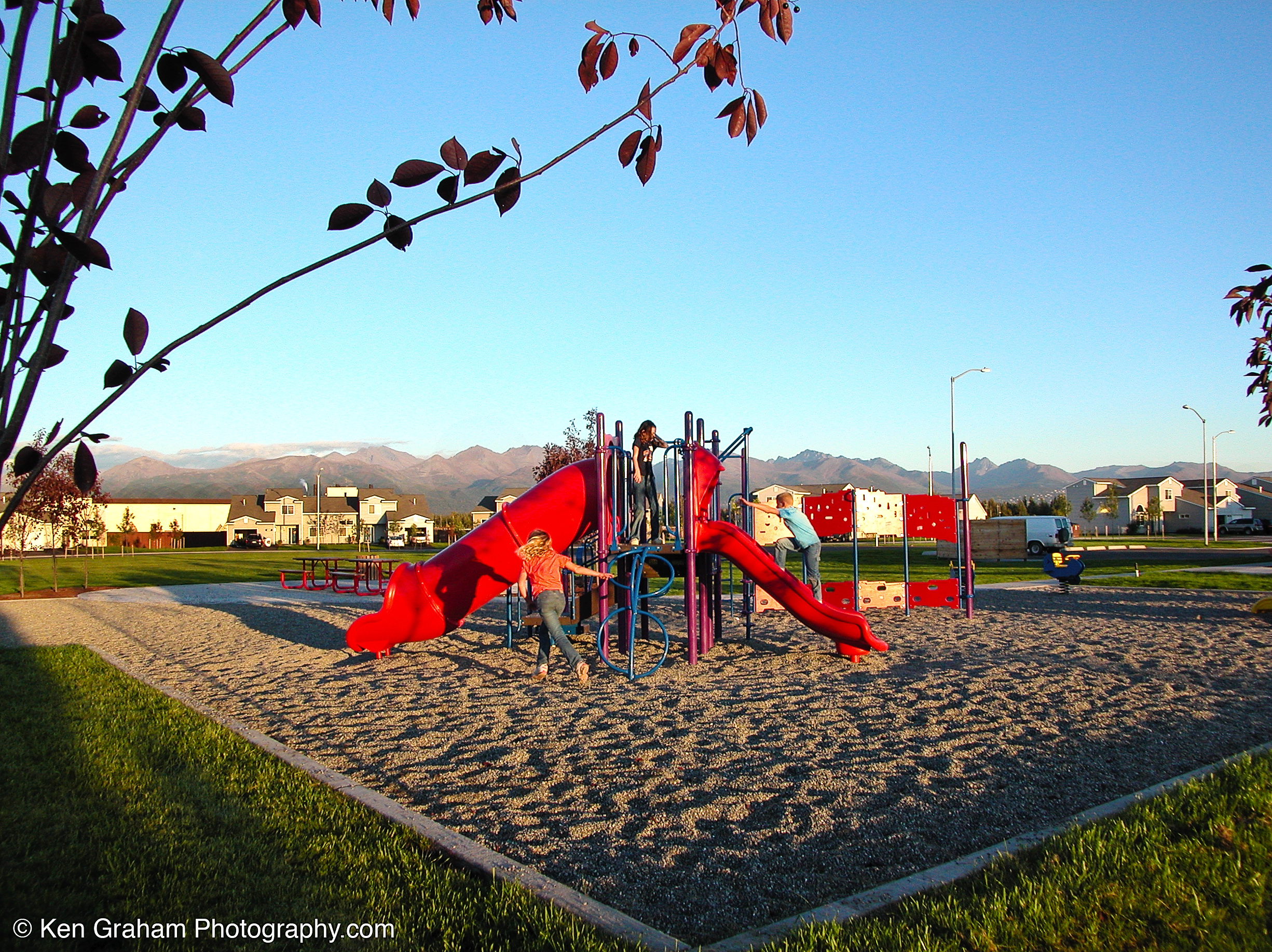 Golden midday light shines on a playground in Alaska in the summer.