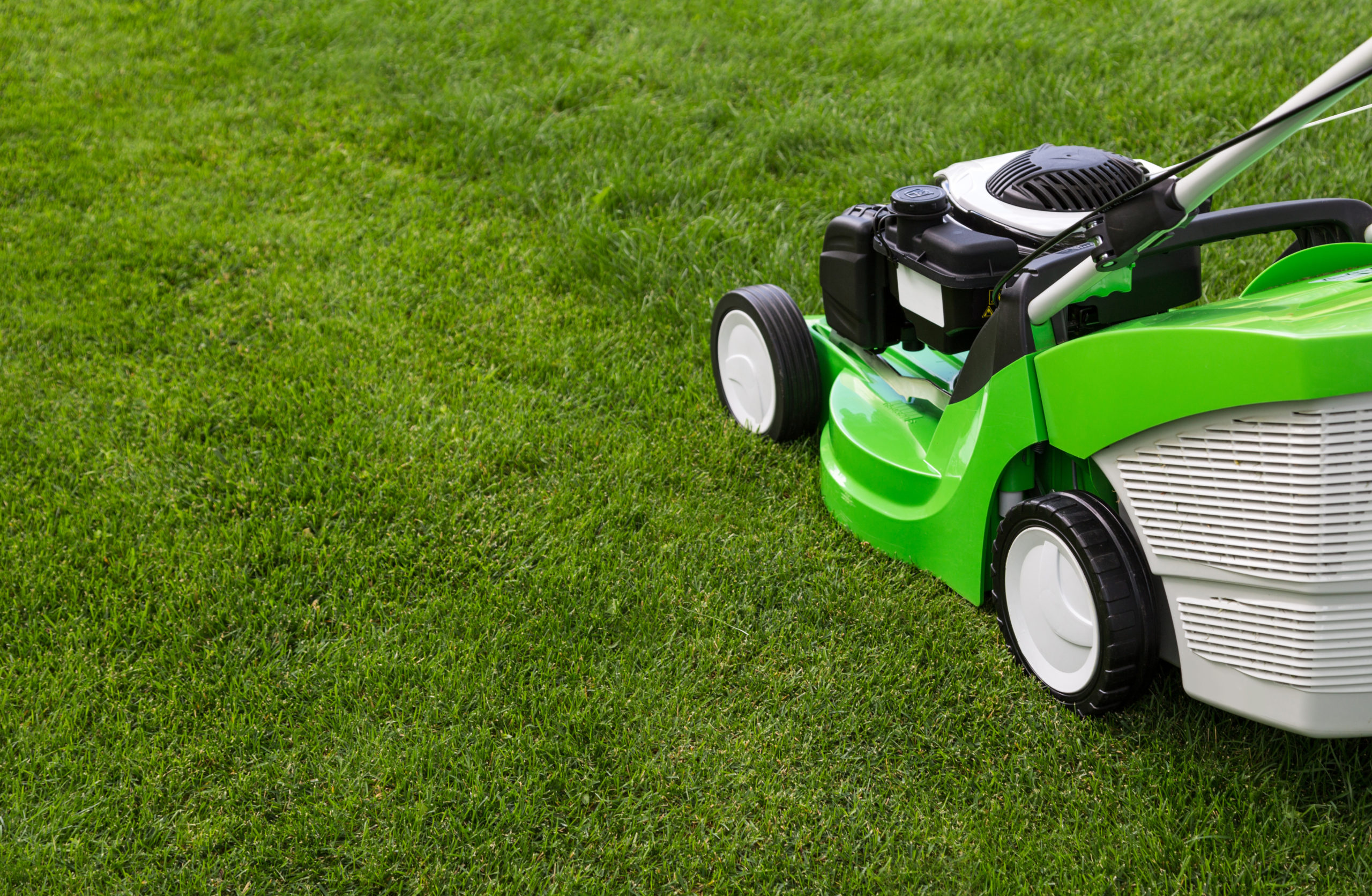 Outdoor shot of green lawnmower on a newly cut green lawn