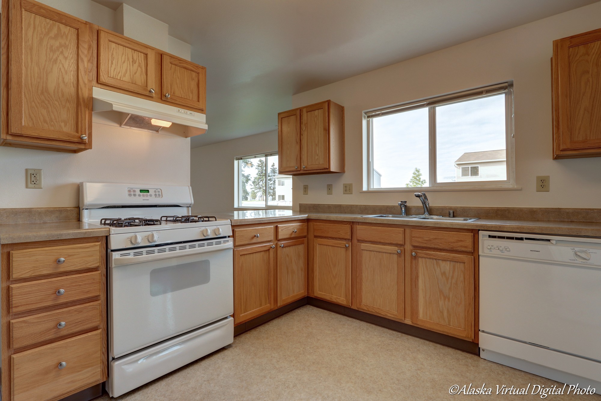 Image of kitchen with wooden cabinets and large window above sink