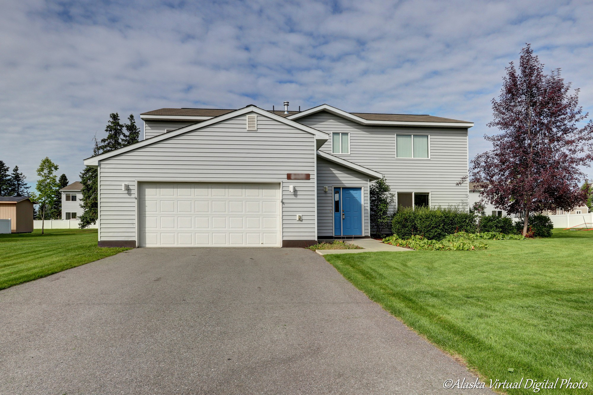 Exterior of gray home with blue door and green grass