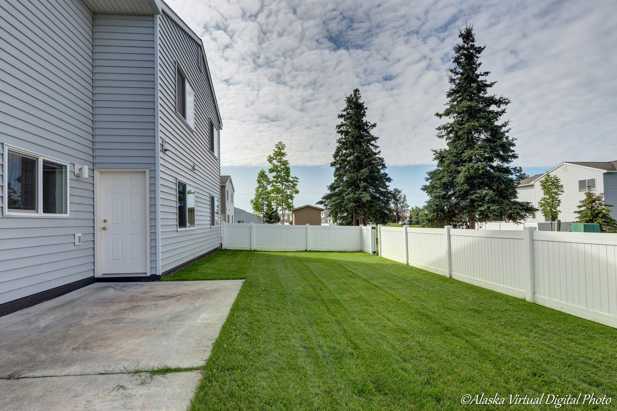 Image of back yard with white fence and cement patio