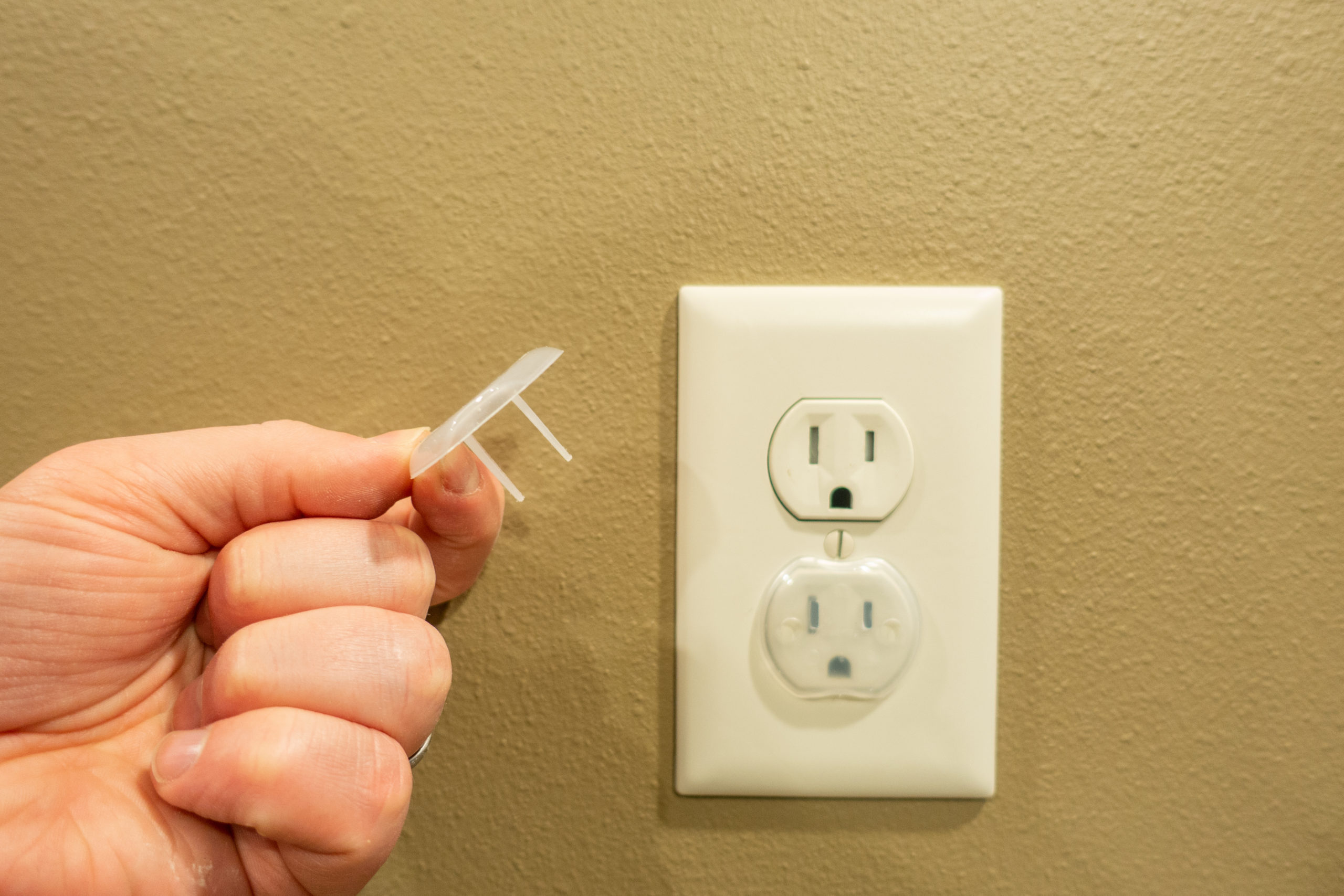 hand placing a childproof outlet cover on an outlet