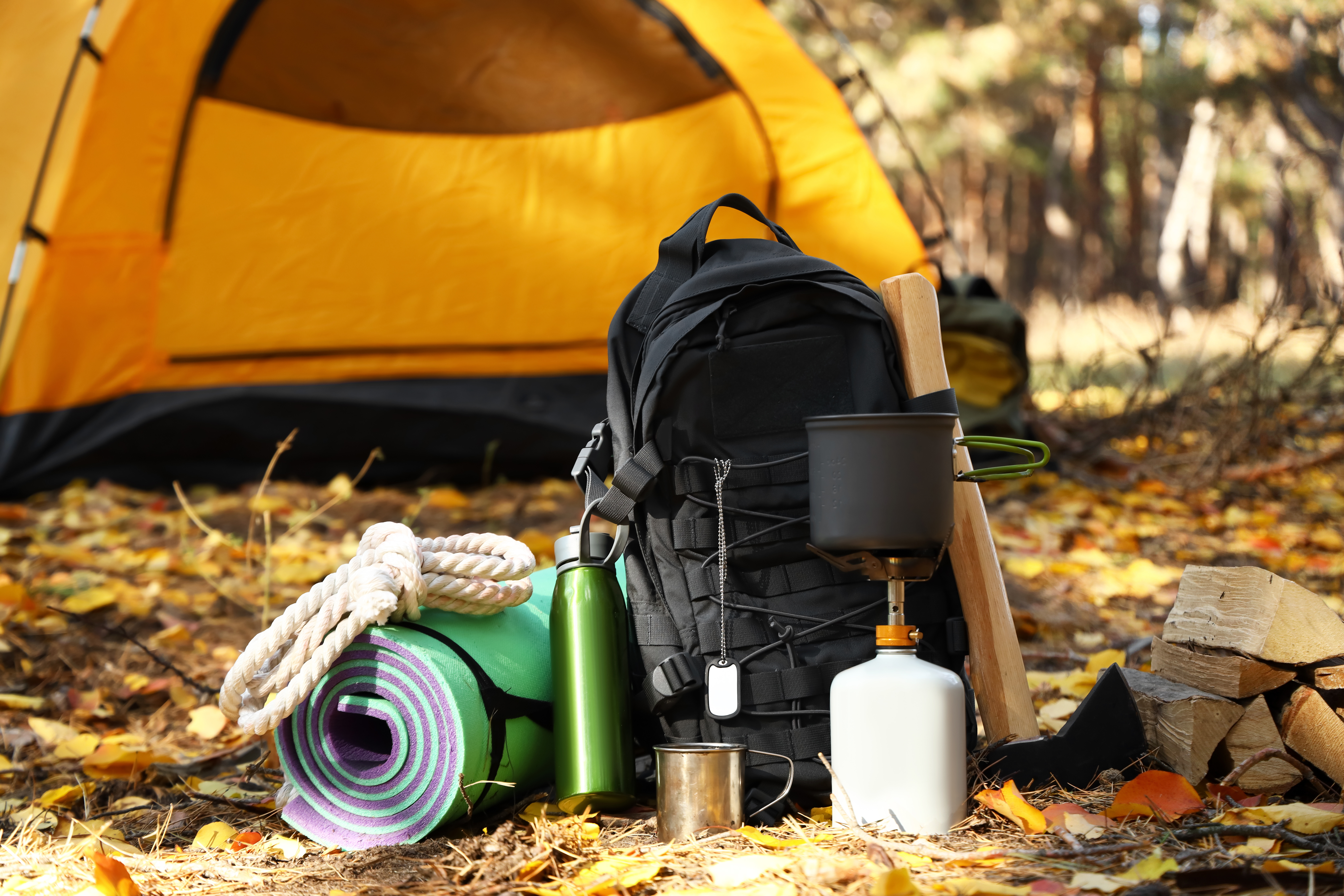 Tourist's survival kit and camping tent in autumn forest