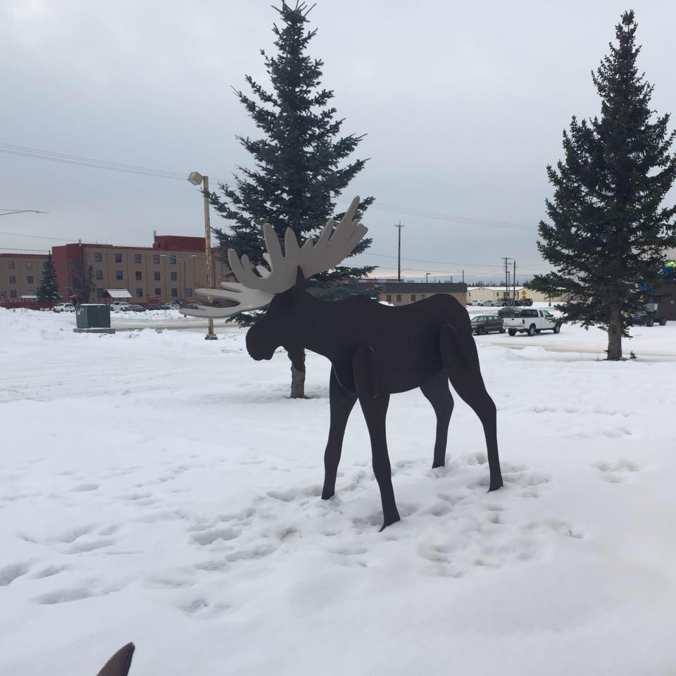 Wooden moose in snowy lawn outside of arts and crafts center