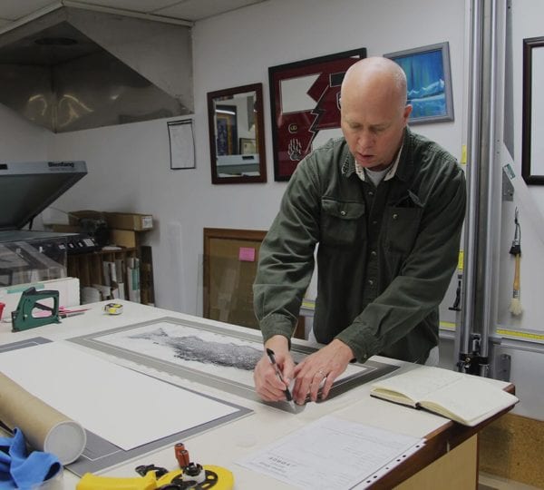 man in uniform working at picture framing station