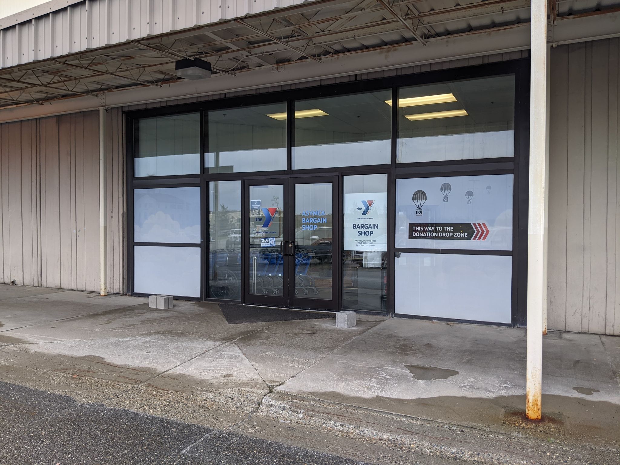 front entrance to asymca bargain shop, tan building with glass doors