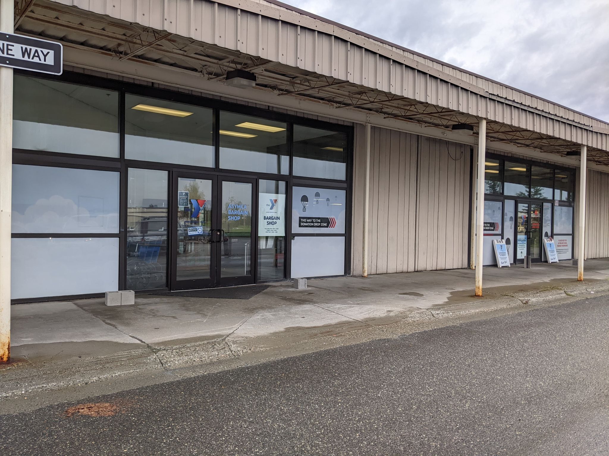 front entrance to asymca bargain shop, tan building with glass doors